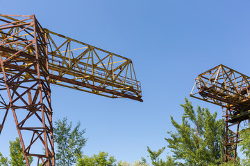 Part two rusty gantry cranes on the background of blue sky.