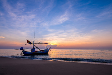 Sunrise on the sea beach with fishing boat