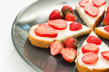 Snacks of fresh sandwiches with strawberries on a white table.