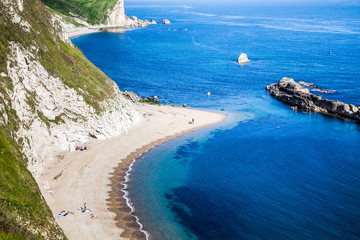 people enjoying a hot summer day on a beautiful hidden beach on the Jurassic Coast of Dorset, UK - Britiish summer holiday destination