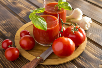 Red tomatoes with tomato juice, garlic and knife on the wooden table