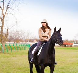  Woman riding horse, beige pullover, jeans, hat, close up