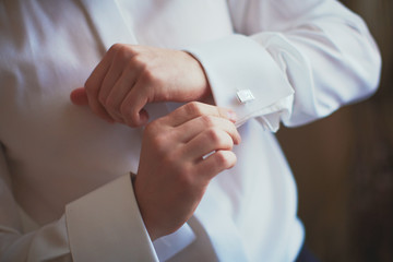 Man is fixing his cufflinks