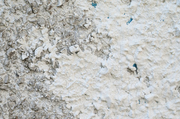 Old white concrete wall with many protruding stones