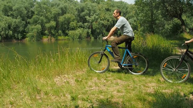 Active rest by the river. Family on bicycles in nature.