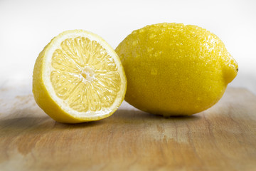 Some yellow, ripe and fresh lemons are on the wood table.