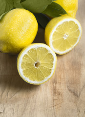 Some yellow, ripe and fresh lemons are on the wood table.