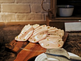 Thin slices of spicy ham on wooden board.