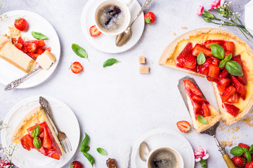 Overhead shot of cups of coffee, delicious homemade strawberry cheesecake and flowers on light gray background. Top view, flat lay. Copy space.
