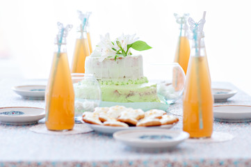 Fototapeta na wymiar Mint-colored cake with handmade cookies and bottled juice