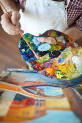 High angle shot of talented artist mixing colors on palette while painting picture in art studio © pressmaster