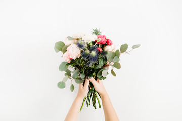 Beautiful flowers bouquet in girls hands: bombastic roses, blue eringium, eucalyptus, isolated on white background. Flat lay, top view. Floral composition