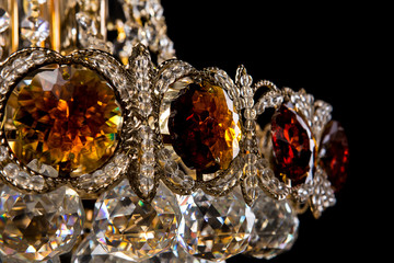 Large crystal chandelier close-up in baroque style isolated on black background.