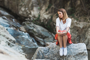 Young woman sitting on the rock by the river thinking