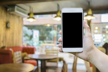 female hand holding mobile smart phone,tablet,cellphone over Blur or Defocus image of Coffee Shop or Cafeteria,Customer at restaurant blur background with bokeh,vintage color,food online call shopping