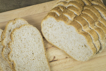 wholegrain rye bread with seeds on a weathered wooden board, rustic earthenware in the dark background