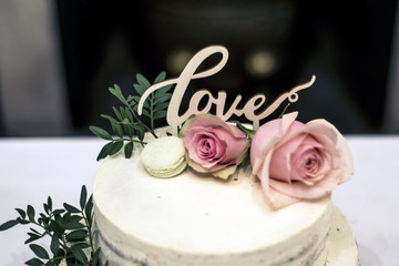 Beautiful wedding cake with cream With text Love on top pink flowers roses