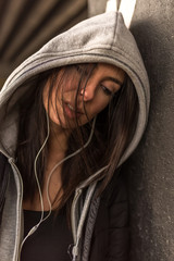 A beautiful young woman listening to Music in a urban environment