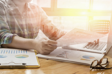 Double exposure of male business mant sitting at wooden desk and using digital computer while typing something on keyboard,freelancer working with laptop, morning light,selective focus,vintage color