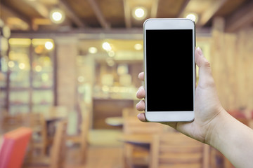 female hand holding mobile smart phone,tablet,cellphone over Blur or Defocus image of Coffee Shop or Cafeteria,Customer at restaurant blur background with bokeh,vintage color,food online call shopping