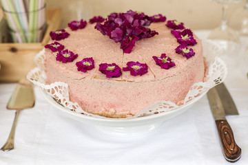 Close up Wedding or birthday cream cake with violet flowers on top silverware