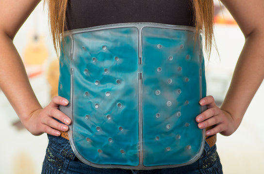 Close up of a female holding ice gel pack on her belly, medical concept, in office background