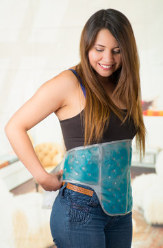 young beautiful woman holding ice gel pack on her belly, medical concept, in office background