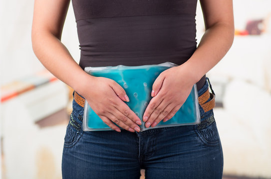 Female holding ice gel pack on her belly , medical concept, in office background