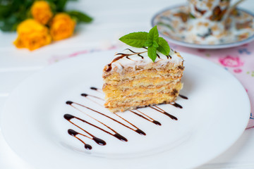 A piece of cake, white cup of tea and strawberries.