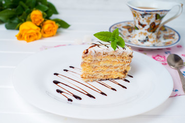 A piece of cake, white cup of tea and strawberries.