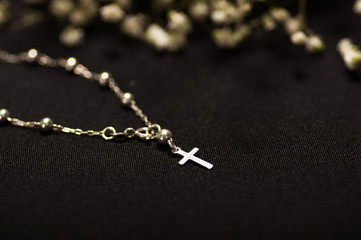 Rosary beads with blurred white small flowers, black background