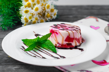 Fruit jelly with pieces of apricots on a plate and spoon on yellow knitted napkin on old wooden table. Selective focus