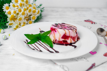 Fruit jelly with pieces of apricots on a plate and spoon on yellow knitted napkin on old wooden table. Selective focus
