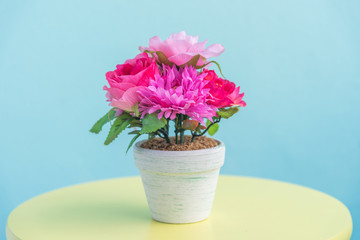 artificial flower pot on wooden table and blue wall background