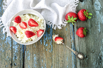 Plate with cottage cheese and strawberries on a wooden table, top view
