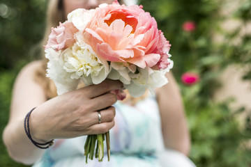 Wedding bouquet of flowers held by bride closeup. Pink flower showing ring