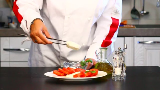 Professional cook prepares a plate with fresh tomatoes and mozzarella