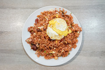 Fried rice with pork and fried egg on a plate and wooden table. Thai food