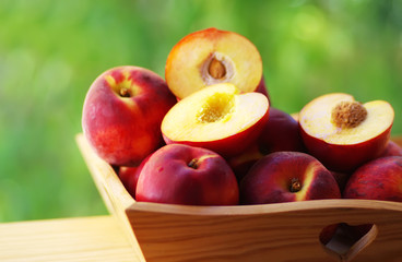 ripe nectarines and peaches on wooden basket