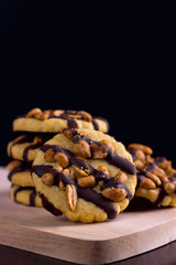 Cookies with peanuts covered with chocolate icing on a dark wooden background.