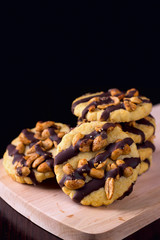Cookies with peanuts covered with chocolate icing on a dark wooden background.