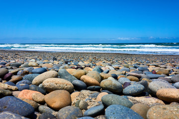runde Steine im Vordergrund, das Meer und die Wellen im Hintergrund