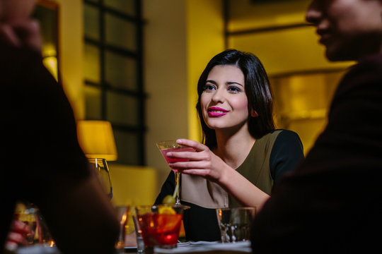 Young woman drinking with friends in restaurant