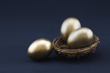 Three gold nest eggs gleam against black background
