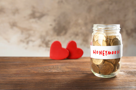 Jar with coins and hearts on wooden table