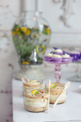 Lemon mousse jars on dessert buffet table at a rustic restaurant with lemonade pitcher in the background.