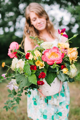 Obraz na płótnie Canvas floral design, wedding, decoration, occasion concept - pretty woman in summer dress puting out grand bouquet of various flowers: big pink peonies, tender avalanches and carnations