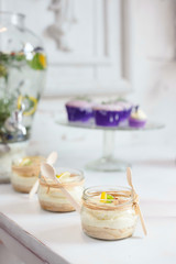 Lemon mousse jars on dessert buffet table at a rustic restaurant with lemonade pitcher in the background.