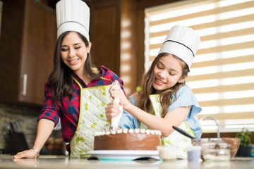 Wearing chef hats and decorating a cake