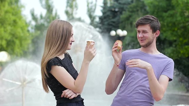 Young couple eating ice cream and having fun at the fountain
